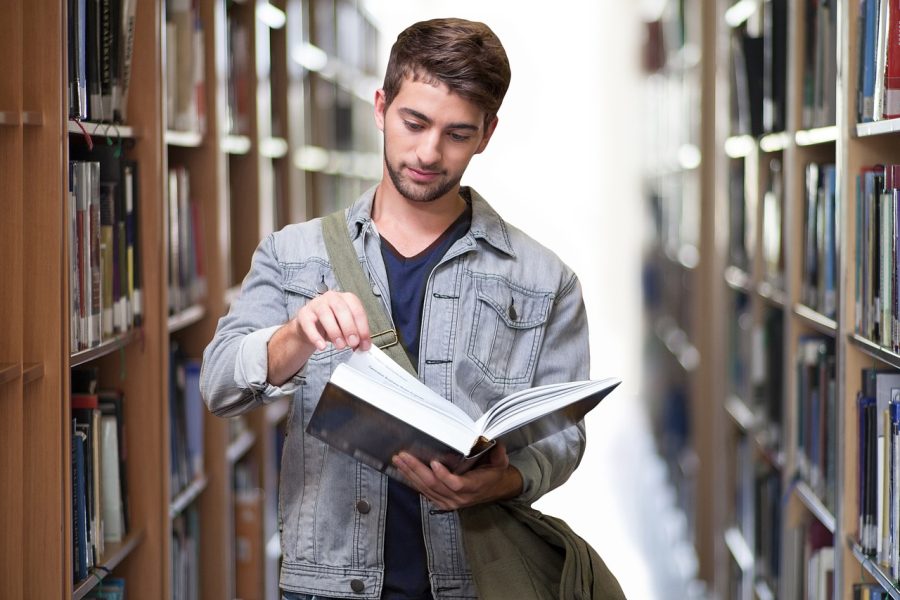 Homem lendo livro na biblioteca